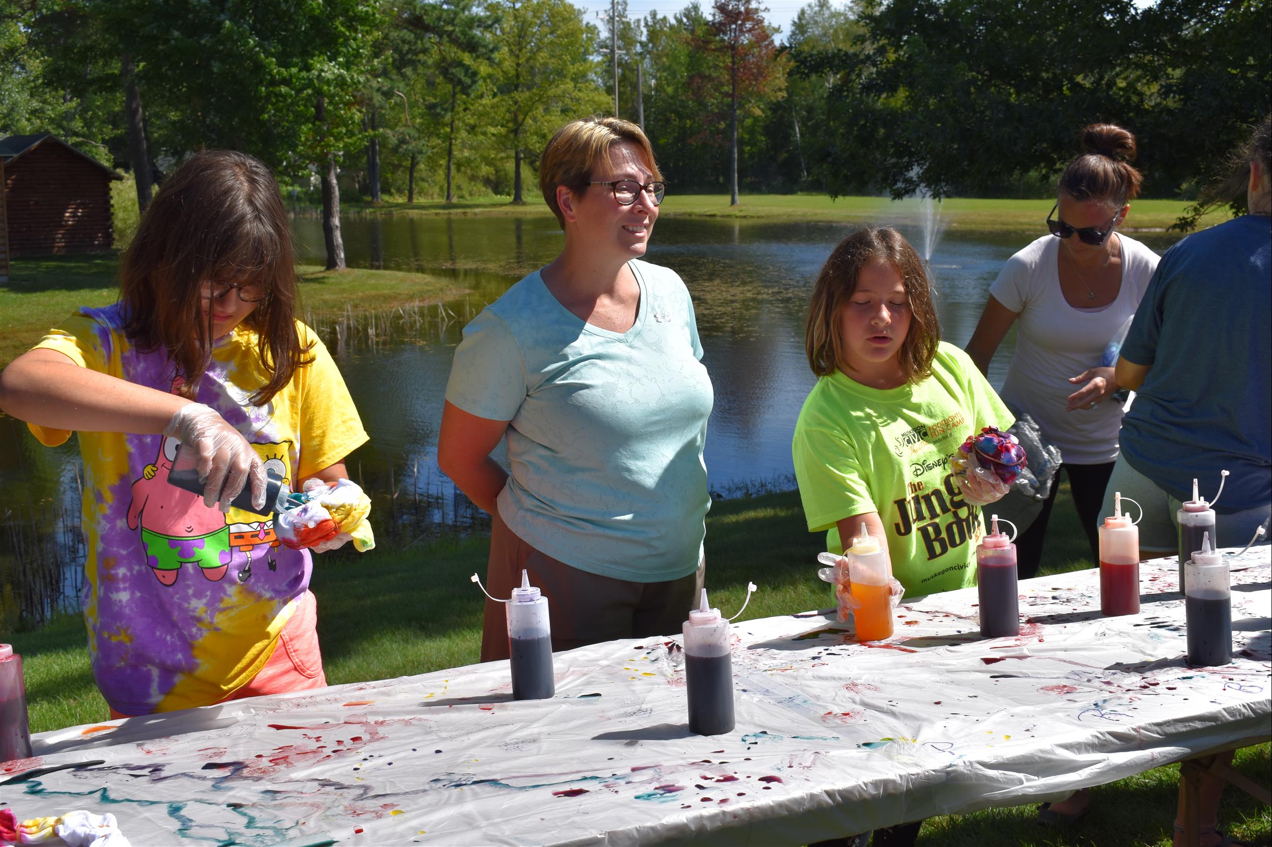 Park guest making tie-dye shirts outside by pond